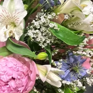 Alstroemère blanche et ses boutons fermés au-dessus d'une pivoine rose, avec statice blanc et nigelle bleue