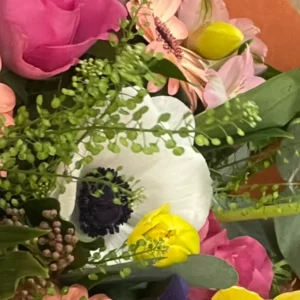 Anémone blanche à cœur noir dans un bouquet, ses tépales arrondis entourant une masse serrée d'étamines sombres