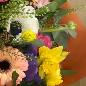 Deux anémones dans un même bouquet, l'une blanche à cœur noir, l'autre bleu-violet, près d'un gerbera saumon