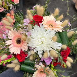 Composition d'automne où le chrysanthème blanc voisine avec des gerberas saumon, des roses rouges et du lagurus