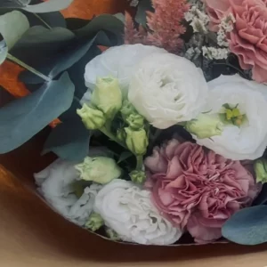 Tige de lisianthus portant à la fois des fleurs blanches ouvertes et des boutons verts pointus encore fermés, parmi des feuilles d'eucalyptus