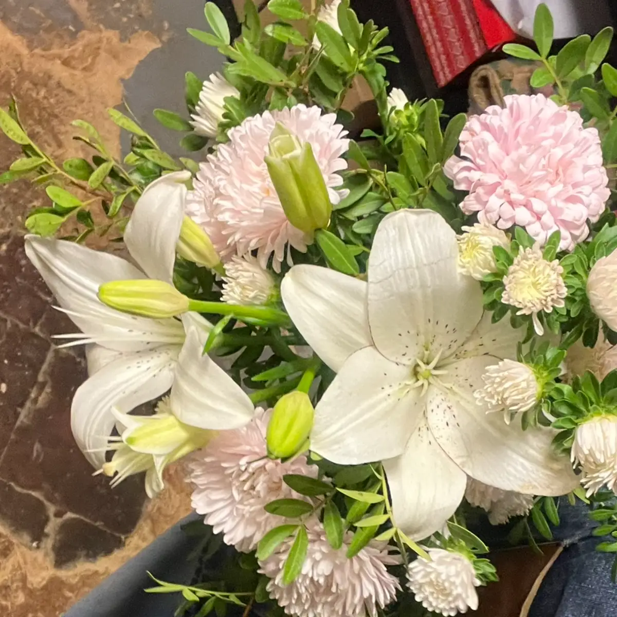 Lys blancs épanouis et boutons fermés dans un bouquet, entourés de reines-marguerites roses